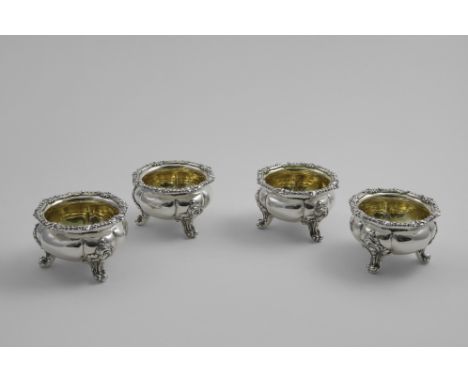 A SET OF FOUR EARLY VICTORIAN SALTS of shaped circular outline on three decorative scroll feet with gadroon &amp; foliate bor