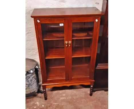 A 77cm reproduction mahogany book cabinet with adjustable shelves enclosed by a pair of glazed panel doors, set on bobbin tur