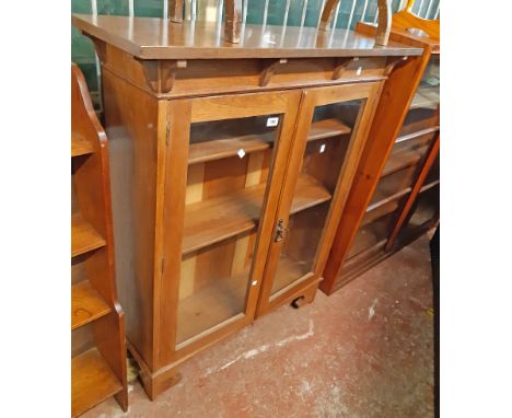 A 1.04m early 20th Century Arts &amp; Crafts style book cabinet with adjustable shelves enclosed by a pair of glazed panel do