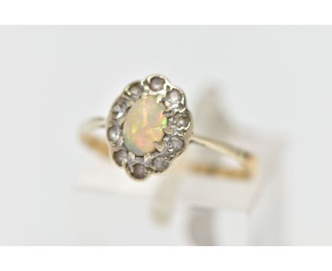 A MID 20TH CENTURY OPAL CLUSTER RING, set with a principal oval opal cabochon, within a colourless gemstone surround, to the 