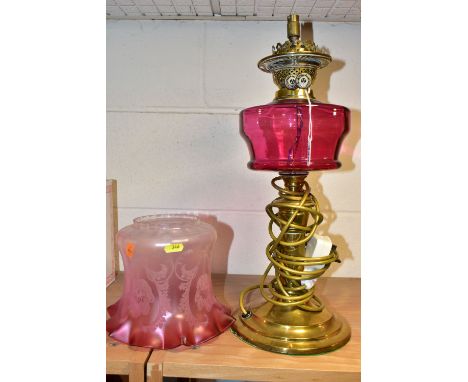 AN EARLY 20TH CENTURY BRASS BASED OIL LAMP CONVERTED TO ELECTRICTY, acid etched opaque cranberry glass shade, cranberry glass