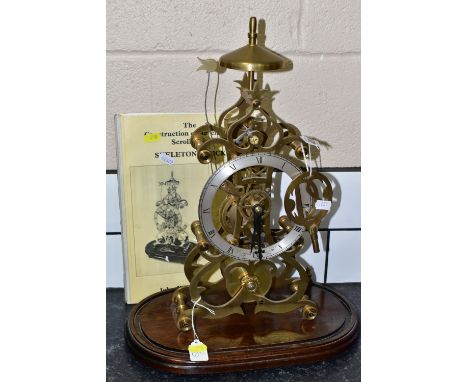 A LATE 20TH CENTURY DENNIS SMITH BRASS SKELETON CLOCK OF SCROLLED FORM, the silvered chapter ring with Roman numerals and nam