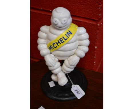 A reproduction cast metal figure of a  Michelin man sitting on a stool.