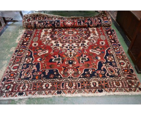 A substantial Iranian rectangular wool carpet, embroidered in coloured threads in the typical manner with geometric devices, 