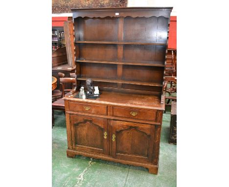 An oak dresser, three shelves and shaped uprights to top, two drawers over two fielded panel door cupboard to base 