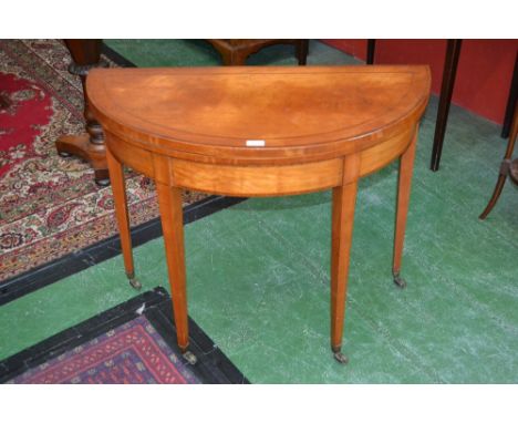 A George III rosewood crossbanded satinwood demi-lune card table, folding top above a deep frieze, tapered square legs, brass