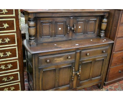 An oak court cupboard, two panel doors flanked by turned columns to top, two short drawers over two panel door cupboard to ba