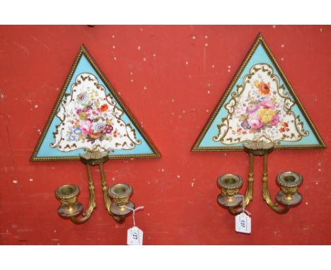 A pair of early 20th century gilt metal two-light wall sconces, the triangular porcelain panels  painted with colourful summe