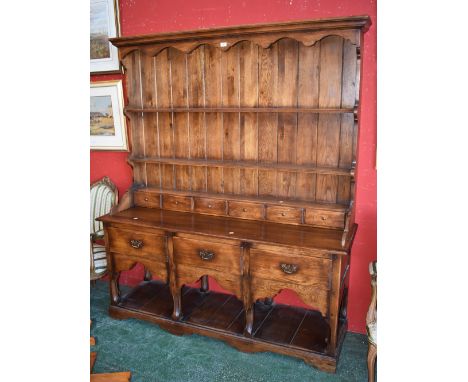 A 20th century reproduction oak dresser, plate rack back, frieze drawers, open base shelf