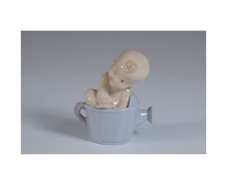 This endearing Nao porcelain figurine, titled "From a Sunflower?", features a baby seated in a delicate flower, part of the "
