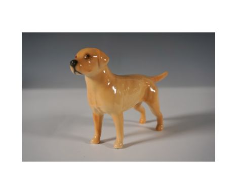 A finely crafted Beswick porcelain figurine depicting a Labrador Retriever in a standing pose. Finished in a warm honey-color