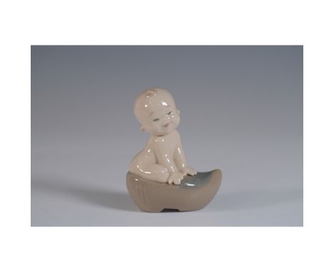 This Nao figurine features a charming baby sitting on a shoe, crafted with delicate attention to detail. The figurine measure