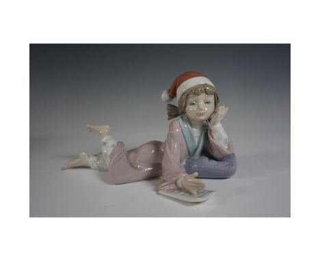 This delightful piece features a young girl wearing a Santa hat, lying on a cushion as she writes her holiday wishes. Crafted