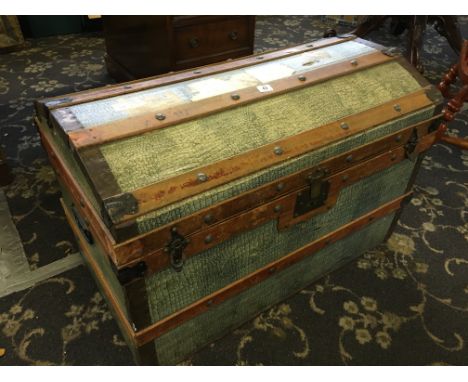 A late 19th century dome top trunk with paper crocodile skin effect decoration and travel labels.