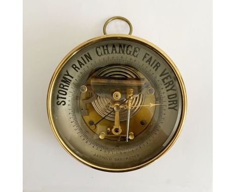 Edwardian gilt brass cased aneroid skeleton barometer, with glass front, blued steel and gilt metal handle, 17cm diam.&nbsp;