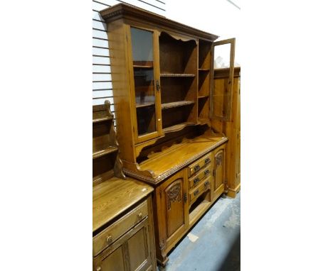 Arts & Crafts-style oak dresser, the ogee moulded cornice above assorted shelves and two glazed doors, the base of three draw