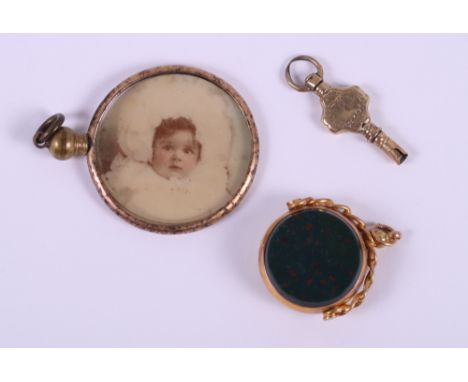 A 9ct gold fob spinner set bloodstone and carnelian, a 19th century yellow metal watch key and a rolled gold framed locket