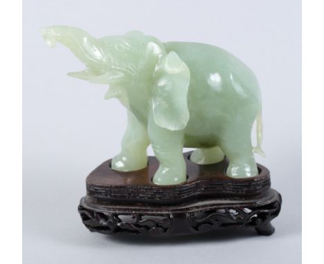 A carved jade elephant, on carved wooden stand, 4 1/4" high (damages), and a pale celadon carved pig, 1 1/4" long
