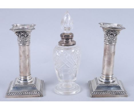 A pair of silver filled pillar candlesticks, on square bases, and a silver mounted toilet bottle