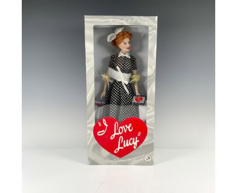 Lucy dressed in a classic black and white polka dot dress, elegantly accented by a white ribbon adorning her signature red ha