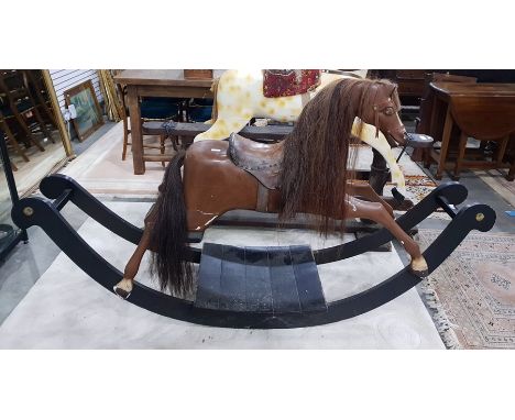 19th century carved wood child's rocking horse with horse hair mane and tail, brown leather saddle, raised upon a black paint