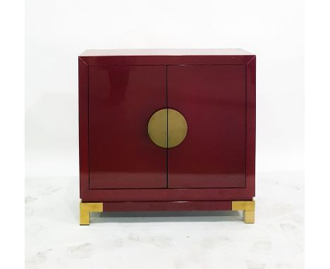 Red lacquer side cupboard, the pair of doors with circular brass handles enclosing two shelves, raised on brass faced bracket