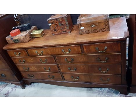 Early 20th century mahogany veneered and cross-banded dressing chest having an arrangement of nine drawers, with moulded gilt