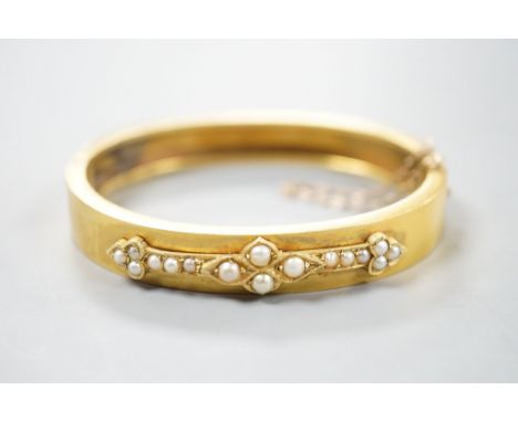 A Victorian yellow metal and split pearl set hinged bangle, interior diameter 55mm, gross weight 15.6 grams.