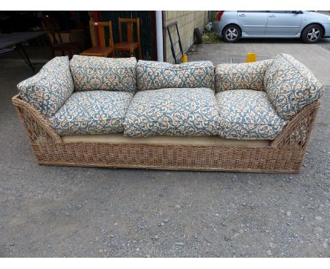 Large cane sofa with cushions, some damage.