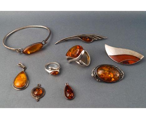 A collection of white metal and amber jewellery, comprising three pendants, three brooches, two rings and a bangle