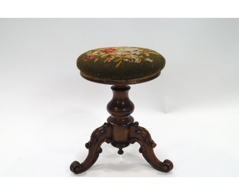 A Victorian revolving rosewood piano stool with tapestry seat on three carved legs, 49cm high