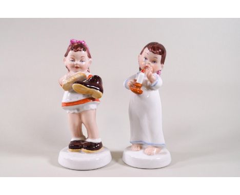 A pair of Royal Dux porcelain figures of children, one cleaning a shoe and the other holding a chamber stick, 14cm high