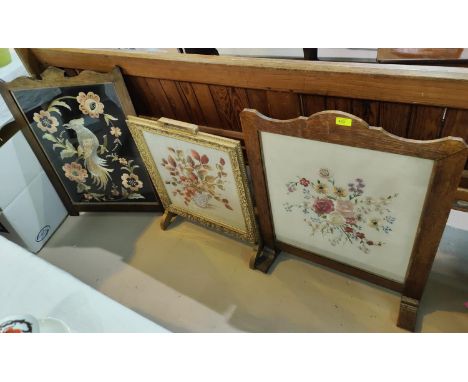 An oak framed firescreen with floral work display; another in gilt and cream; another (no supports) 