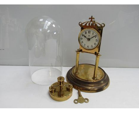A brass anniversary clock with Arabic enamelled dial, key, pendulum and glass dome