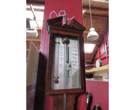 A mahogany stick barometer with broken pediment top, open mercury tube and glazed door over silvered scales