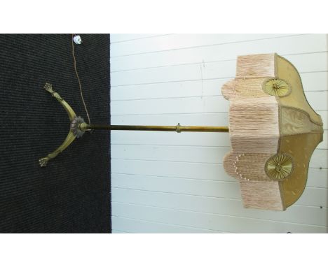 A late 19th Century brass standard lamp with tasselled shade, paw feet