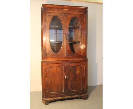 EARLY 19TH CENTURY WELSH OAK NOW GLAZED TWO STAGE STANDING CORNER CUPBOARD having moulded cornice over veneered and banded fr