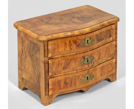 Barock-Modellkommode Nussbaum, furniert. Gerader, querrechteckig angelegter Korpus mit gesägten Füßen. In der gegliederten Fr