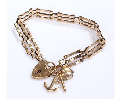 9 carat gold gate bracelet, of typical form with a heart shaped padlock clasp and three charms in the form of a cross, an anc