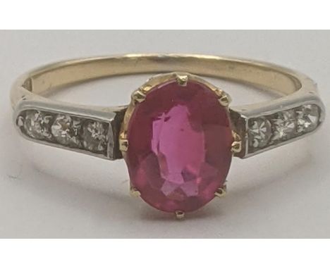 18ct yellow and white gold ring set with an oval cut synthetic ruby in a 8 claw setting flanked by three shoulders in channel