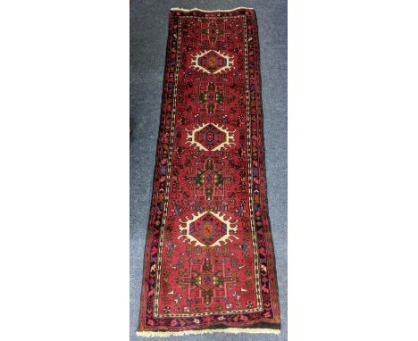 A Persian red ground runner having repeating motifs surrounded by a floral design, 205cm x 67cm Location:If there is no condi
