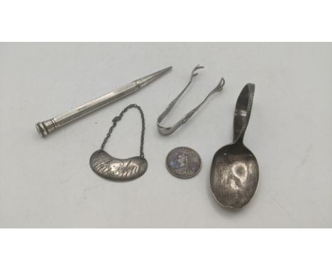 A mixed silver collectables to include a tea caddy spoon A/F, a label 'whisky', a pair of sugar tong, an 1887 British coin an
