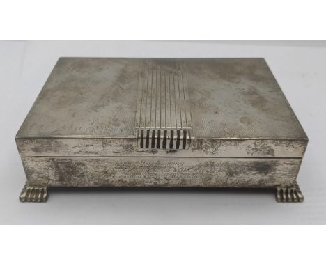 A silver cigarette box having and engine turned lid on four feet with engraved inscription to the front, hallmarked Birmingha