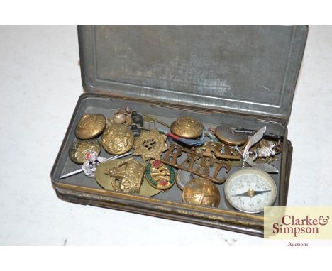 A King George V tin containing various mixed military badges, compass etc. 