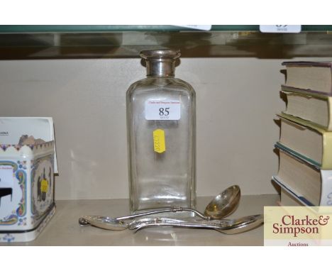 A silver topped glass bottle and a quantity of silver spoons 