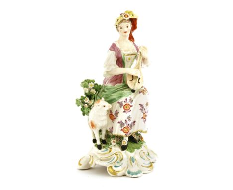 A Derby figure of a shepherdess , c.1765, with a flowing headdress, seated playing a lute with a lamb beside her, on a scroll
