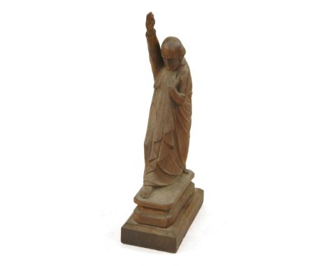 A carved oak figure, 20th century , of a clergyman holding one arm aloft whilst clutching his cloak, mounted on a rectangular