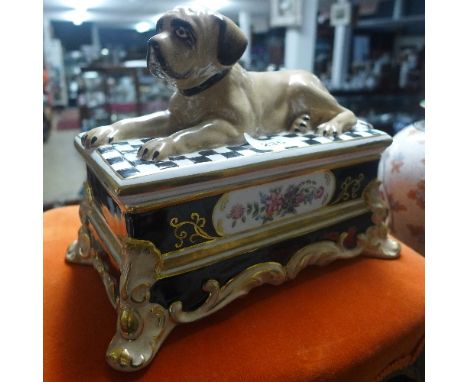A pottery trinket box with dog finial, seated on chequered rug