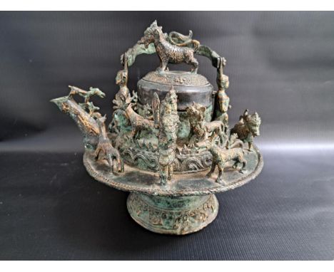 19th CENTURY MALAY BRONZE KETTLEwith a fold over lizard decorated handle with grotesque figures to the hinges, above a circul