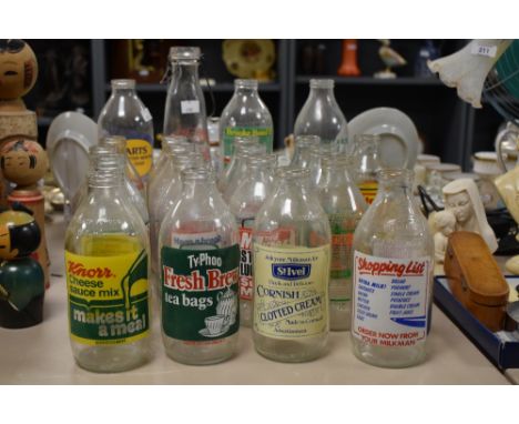 A group of twenty one vintage milk bottles having various advertisements including Ty-Phoo Fresh Brew tea bags, Start your da